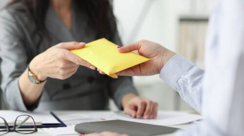 Woman hands over full envelope to her interlocutor. Salary in an envelope concept